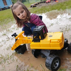 Mädchen mit Bagger in Pfütze