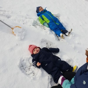 Zwei Kinder liegen im Schnee